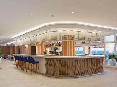 Bright, modern hotel bar area with curved wooden counter and blue bar stools.