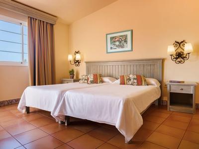 Camera doppia con illuminazione calda, due letti e cuscini decorativi in un ambiente tranquillo.