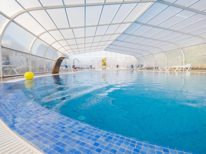 Piscina riscaldata con copertura e palline gialle in un hotel.