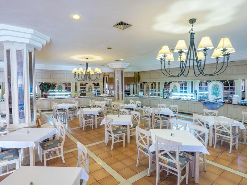 Ampia e luminosa sala da pranzo con mobili bianchi e lampadari.