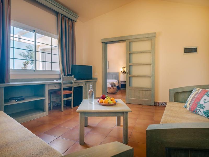 Soggiorno accogliente con divano, tavolo, TV e vista su un'altra stanza.