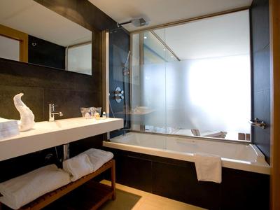 Modernes Badezimmer mit Badewanne, großem Spiegel, Waschbecken und Holzregal unter dem Waschtisch.