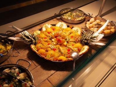 Buffet mit einer großen Platte gefülltem Reis, Garnelen, Gemüse und weiteren Schalen mit Speisen.