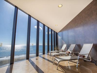 Nowoczesny pokój relaksacyjny z leżakami i oknami od podłogi do sufitu z widokiem na morze.