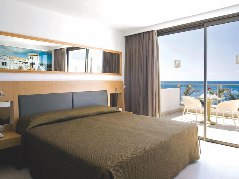 Moderne hotelkamer met een groot bed en balkon met uitzicht op zee.