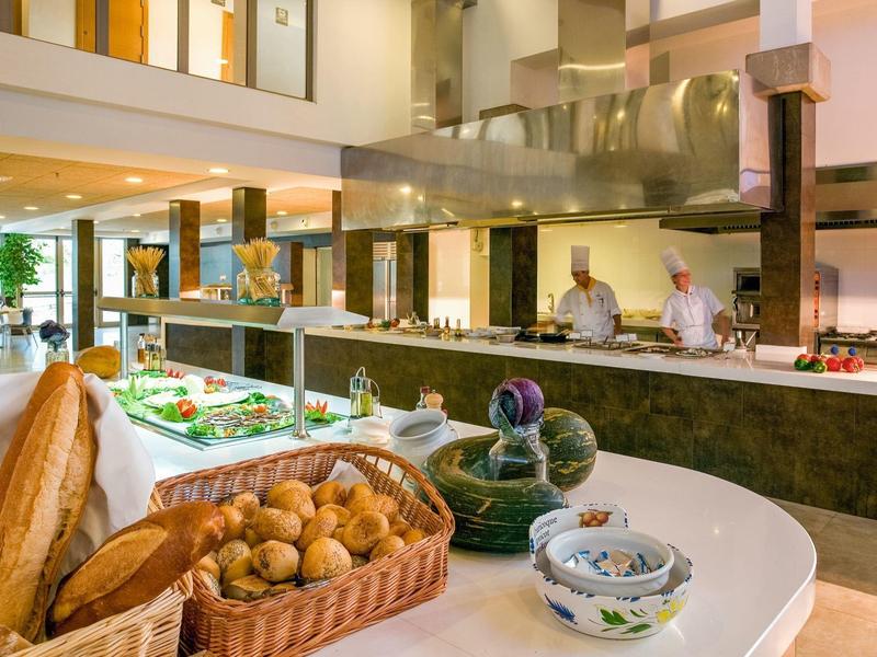 Buffet met brood, gebak en koks in een moderne hotelkeuken.