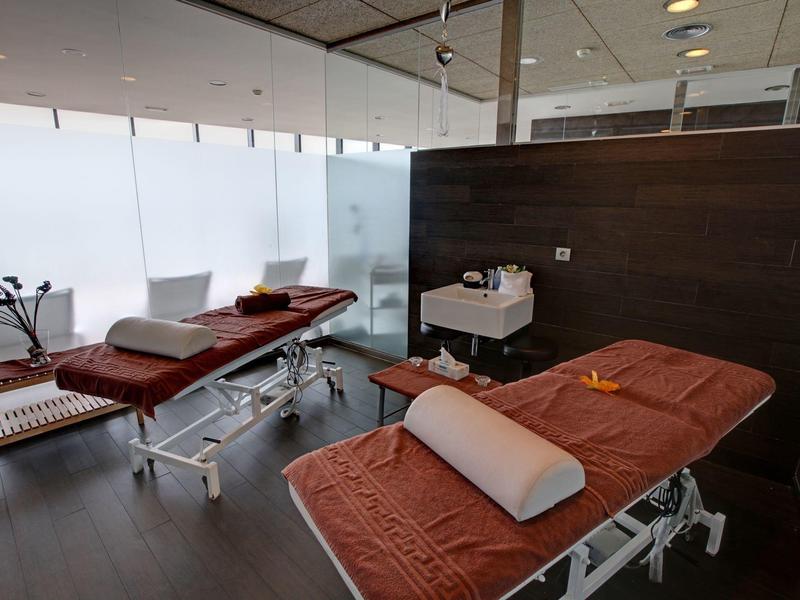 Moderne spakamer met twee massagetafels, zachte kussens en privacy schermen.