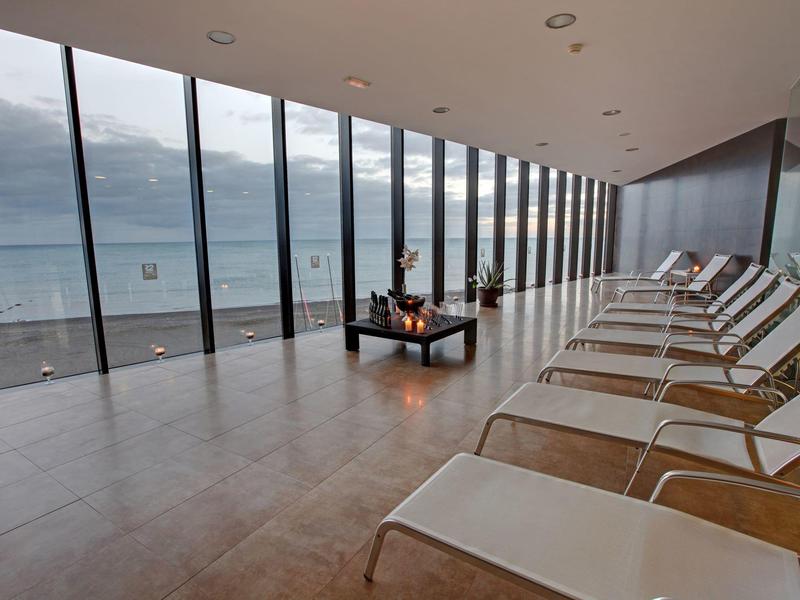 Moderne lounge met witte stoelen en uitzicht op de oceaan door grote glazen wanden.