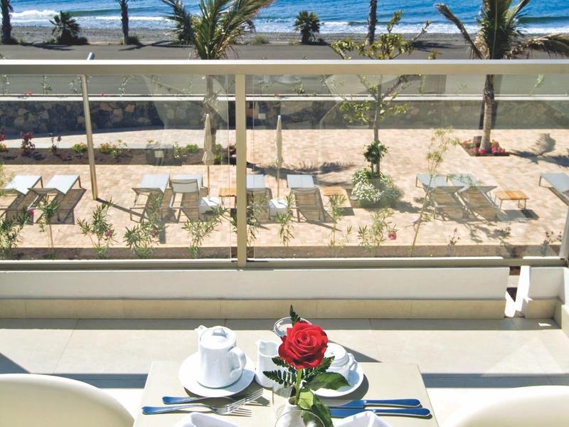 Moderne kamer met grote ramen aan de vloer, uitzicht op de oceaan, salontafel met brandende kaarsen en schaakspel.