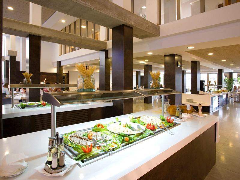 Goed verlichte buffetstation met verse salades en modern interieur in een ruime eetzaal.