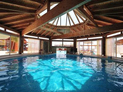 Piscina interior con agua clara y techo de vigas de madera en un hotel.