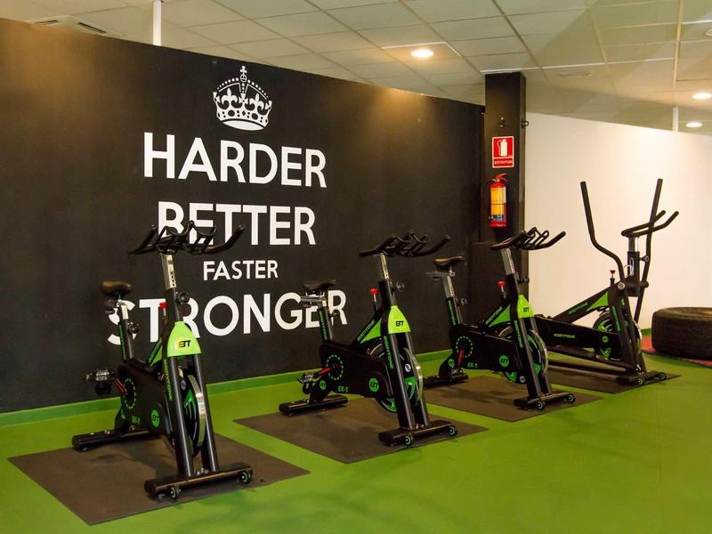 Fitness room with several indoor bikes in front of a wall with motivational text.