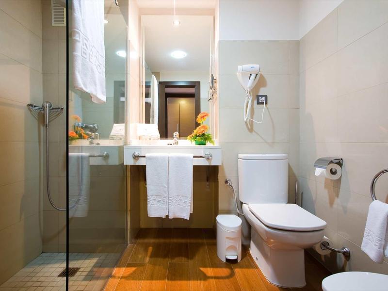 Modern bathroom with shower, toilet, sink, and towels in a hotel room.
