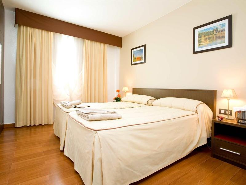 Bright and cozy hotel room with two single beds and bedside lamps.