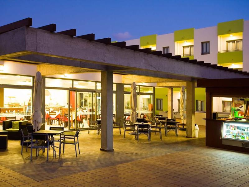 Evening hotel terrace with seating areas and outdoor bar.