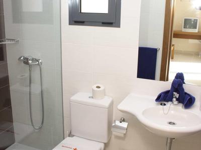 Kleines Badezimmer mit Toilette, Waschbecken, Spiegel, Duschkabine und weißem Wäschekorb.