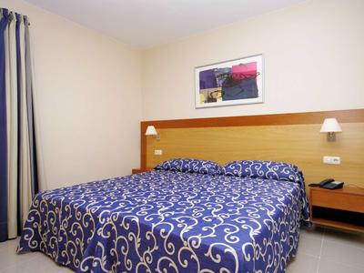 Hell eingerichtetes Schlafzimmer mit großem Doppelbett und blauen Bettdecken mit Muster.