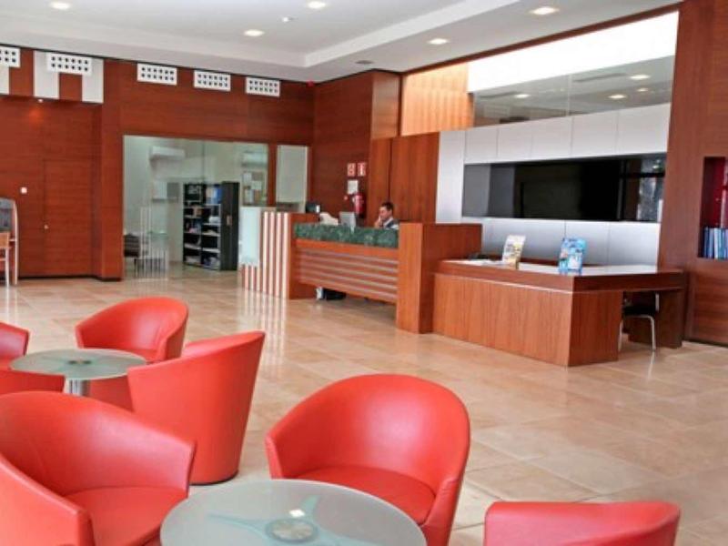 Moderne hotelreceptie met rood meubilair en houten balie.