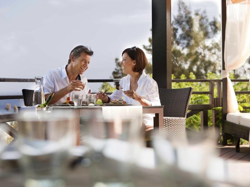 Ein Paar sitzt draußen an einem Tisch, trinkt Wein und unterhält sich entspannt.