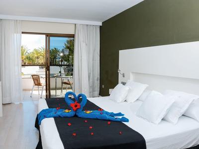 Modernes Schlafzimmer mit weißem Bett, blauer Herz-Dekoration und Balkon mit Holzstuhl.