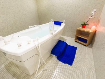 Vasca idromassaggio bianca moderna con asciugamano blu e mobile in legno in bagno luminoso.