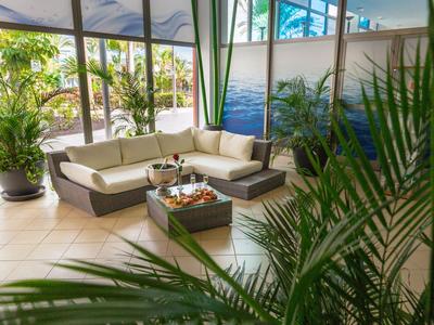 Accogliente angolo lounge con divano e piante in un ampio spazio interno di un hotel.