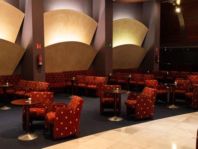 Lounge di un hotel moderno con sedie rosse a pois e tavoli rotondi sotto illuminazione soffusa