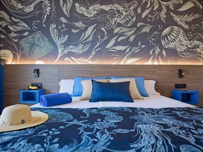 Modern hotel room with large bed, blue decor, and artistic wall design.