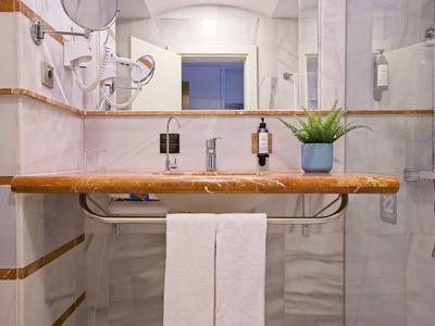 Modern bathroom with wooden shelf, mirrors, and white towels next to a shower cabin.
