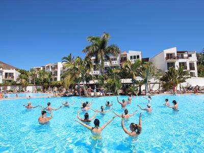 People enjoying water aerobics in a hotel pool under sunny weather