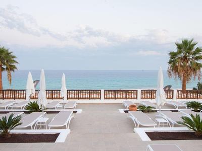Hôtel de plage avec chaises longues, parasols et palmiers au bord de la mer