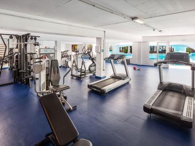 Spacious gym with modern equipment and treadmills in a bright room.