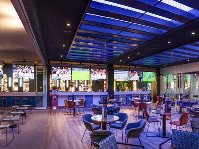 Espace assis intérieur d'hôtel moderne et ouverte avec toit en verre éclairé en bleu et chaises