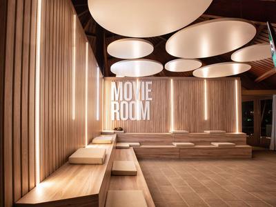 Espace d'attente moderne avec panneaux en bois et grandes lumières ovales au plafond dans la salle de cinéma.