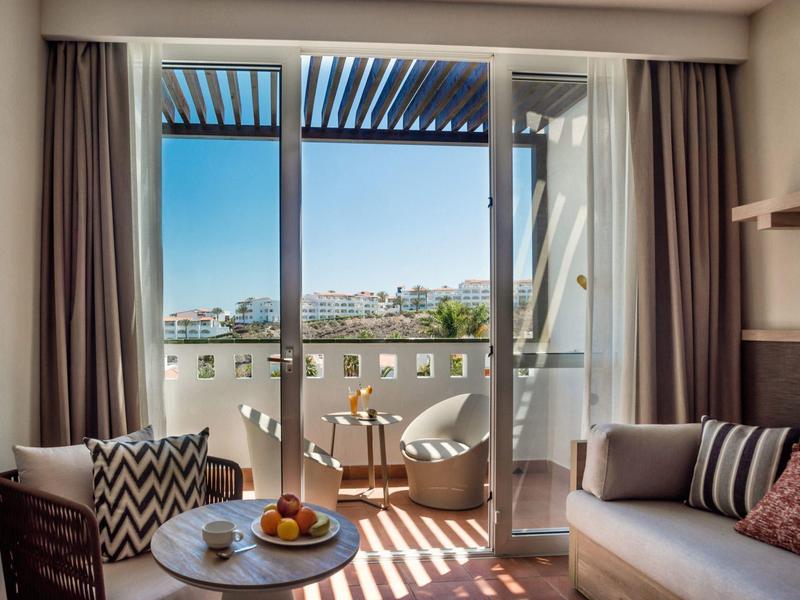 Balcon avec espace salon et vue sur la ville sous un ciel clair dans une chambre d'hôtel