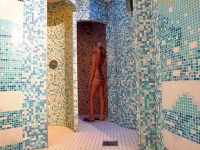 Duschräume mit Mosaikfliesen in Blau- und Weißtönen und einem braunen Vorhang.