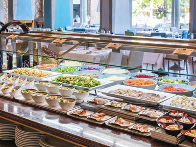 Buffet mit verschiedenen Salaten, Vorspeisen und warmen Speisen in einer modernen Kantine.