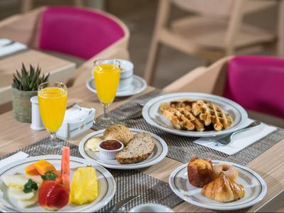 Ontbijttafel met diverse gerechten en twee glazen sinaasappelsap in een restaurant.