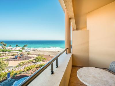 Balkon met tafel en stoel met uitzicht op de zee en een zonnig kustlandschap.