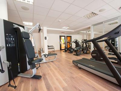 Een moderne fitnessruimte met diverse trainingsapparatuur en houten vloer.
