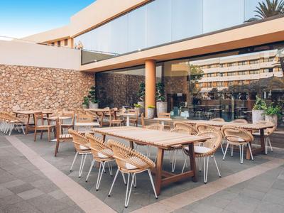Moderne buitenruimte van een hotel met houten tafels en stoelen op een terras.