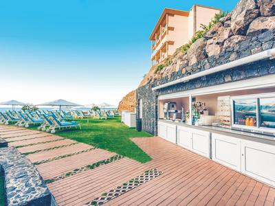 Moderne buitenbar naast een zwembad met ligstoelen en zeezicht.