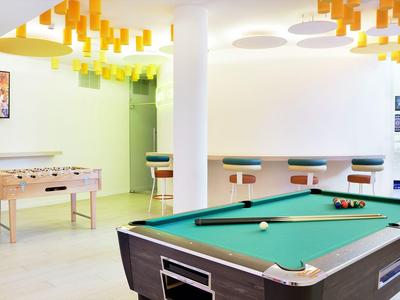 Speelkamer met pooltafel, tafelvoetbal en barkrukken in een moderne omgeving.