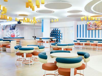 Modern, helder restaurant met ronde tafels, blauwe kussens en opvallend plafondontwerp.