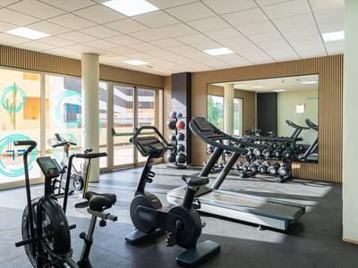 Palestra moderna con cyclette, tapis roulant e parete a specchio.