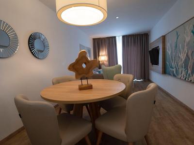 Modern dining area with round wooden table, four chairs, and decorative bird in a hotel room.