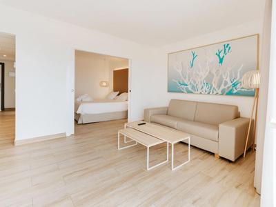 Bright living room with beige sofa, tables, and a coral-themed picture on the wall.