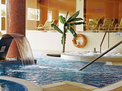Indoor pool with waterfall and seating area in a hotel.