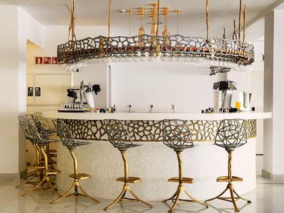 Modern hotel bar area with unique gold-colored bar stools and stylish design.