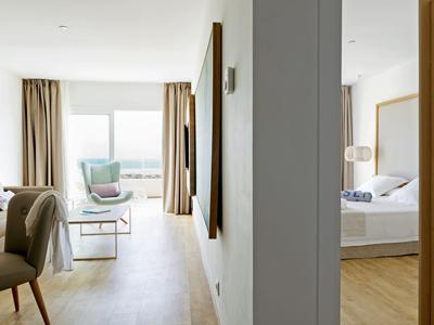 Modern hotel room area with sitting space and bedroom separated by a wall.